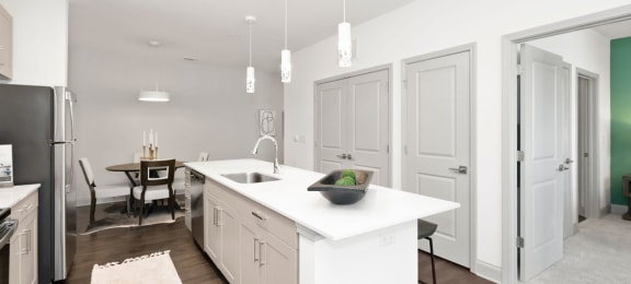 a kitchen with white cabinetry and a large white island with a sink
