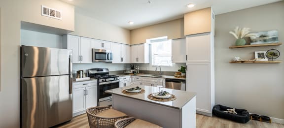 an open kitchen with stainless steel appliances and a island with two stools at SYNC APARTMENT HOMES, Nevada