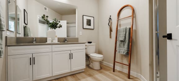 a bathroom with white cabinets and a mirror and a toilet at SYNC APARTMENT HOMES, North Las Vegas, NV 89084
