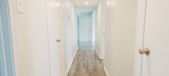 a long white hallway with white walls and wood floors