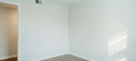 an empty room with a ceiling fan and a carpet