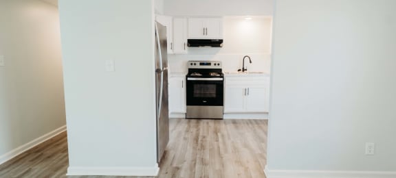 an empty kitchen with white cabinets and a wooden floor