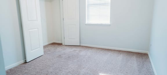 an empty room with a closet and a window