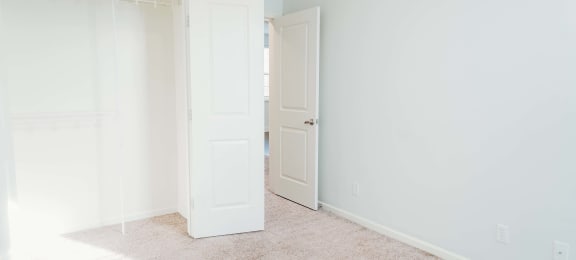 an empty room with a closet and an open door