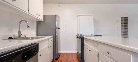 Apartments In San Lorenzo, CA - Lorenzo Commons - A Kitchen With Wood Style Flooring, Stainless Steel Appliances, And White Cabinetry