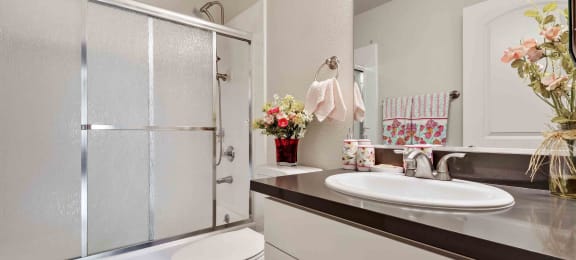 Daly City, CA Apartments - Serra Commons - Bathroom with Glass Shower Sliding Door, Large Mirror, and Tile Flooring
