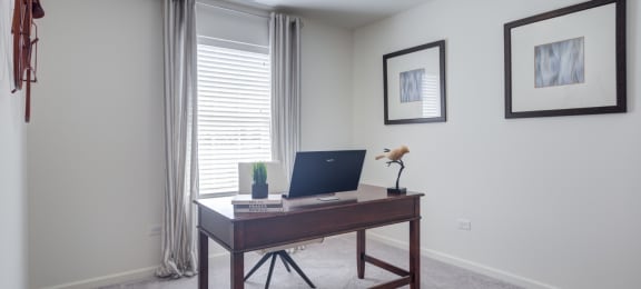 a home office with a laptop on a desk in front of a window