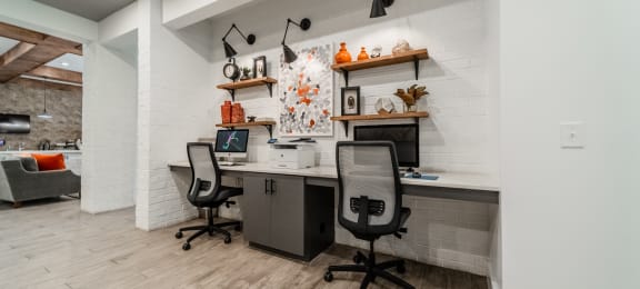 a home office with desks and chairs and a white brick wall