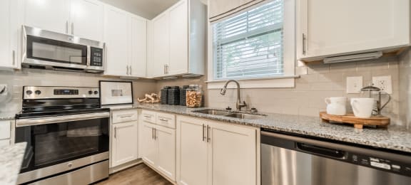 an updated kitchen with stainless steel appliances and granite counter tops
