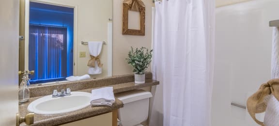 Bathroom with large mirror and white curtains covering tub and shower