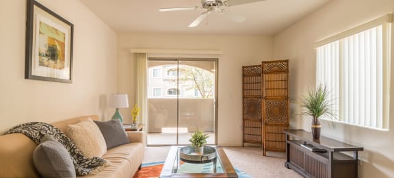 Desert Sands living room with ceiling fan and back sliding door.
