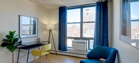 Home office with a blue chair and a desk and a window at Ninth Square Apartments. at Ninth Square Apartments, New Haven