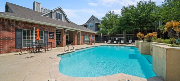 a swimming pool in front of a house with a brick building