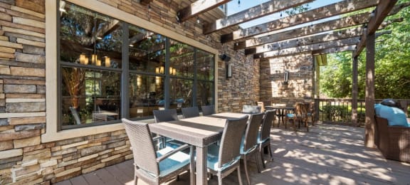 a patio with a wooden table and chairs and a pergola above it