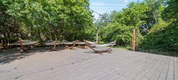 a deck with hammocks and trees in the background