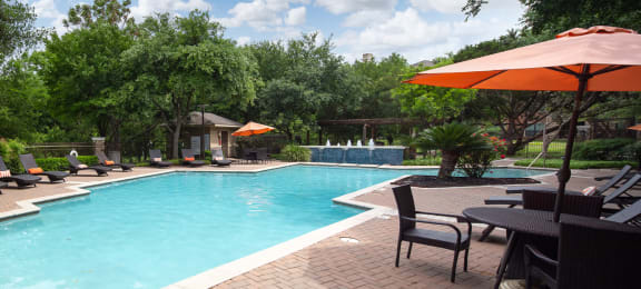 a swimming pool with patio furniture and umbrellas
