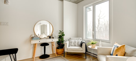 a living room with white furniture and a mirror and a window