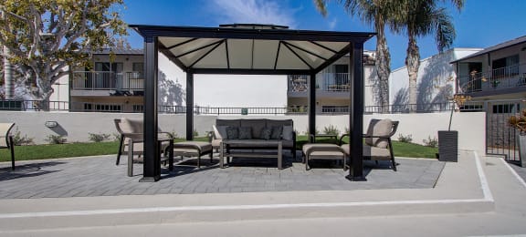 a patio with a couch and chairs under a gazebo