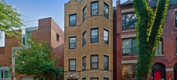 a brown brick apartment building with a red car parked in front of it