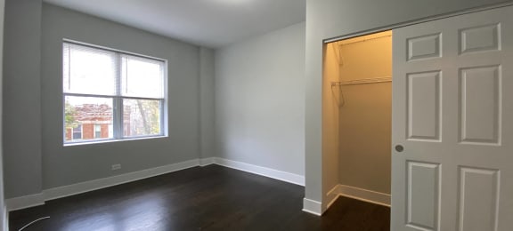 an empty bedroom with a closet and a large window