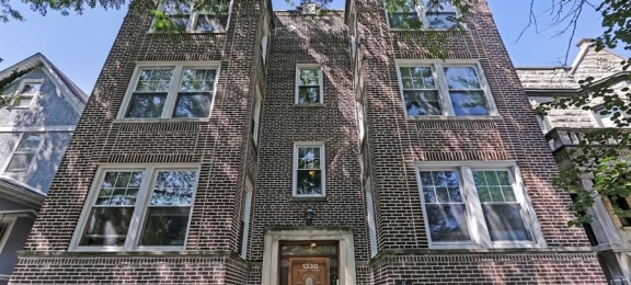 a brick building with a brown door and a white sign in front of it