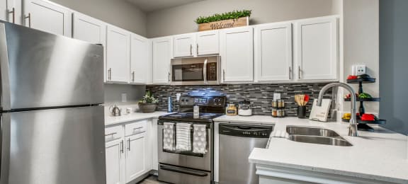Apartments Houston, TX - Large Kitchen with Stainless Steel Appliances, White Cabinets, and Tiled Backsplash