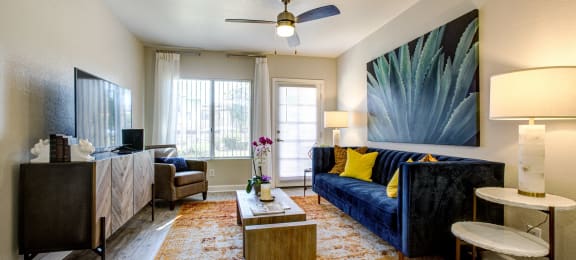 Dog-Friendly Apartments in Phoenix AZ - Village at Lakewood - Living Room with Wood-Style Flooring, Ceiling Fan, and Large Window