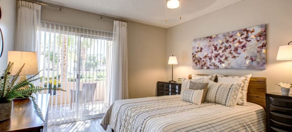 Pet-Friendly Apartments in Phoenix AZ - Village at Lakewood - Bedroom with Wood-Style Flooring and Access to Patio
