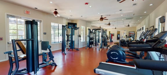 a gym with cardio equipment and ceiling fans