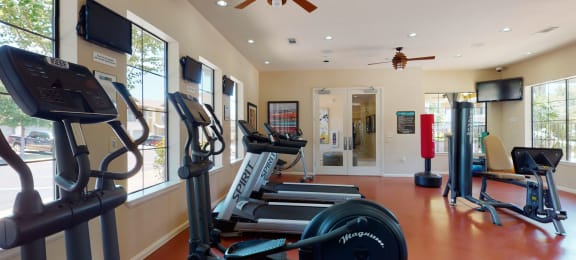 a gym with cardio equipment and a ceiling fan