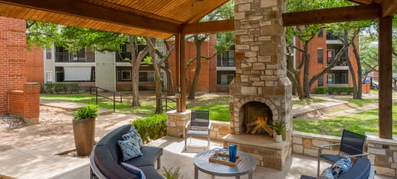 a covered patio with a fireplace and seating
