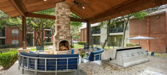 a covered patio with a fireplace and a grill