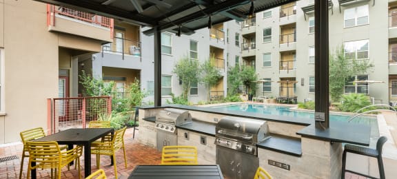 Outdoor patio with a pool and tables and chairs at The Can Plant Residences at Pearl, San Antonio, TX 78215and a white counter top