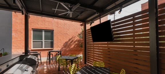 Patio with tables and chairs and a TV at The Can Plant Residences at Pearl, San Antonio, TX 78215