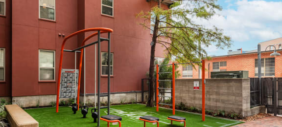 A playground with grass and bench at  The Can Plant Residences at Pearl, San Antonio, TX 78215
