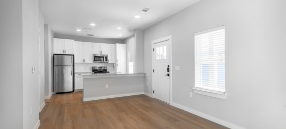 an empty living room and kitchen with white walls and wood floors