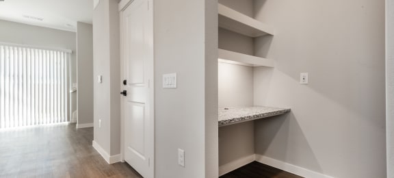 a bedroom with a closet and a door to a hallway with a desk and shelves