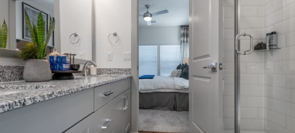 an open bathroom with a shower and a bedroom in the background