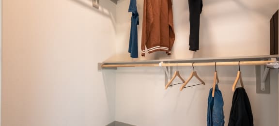 a well lit closet with coats hanging on a rack