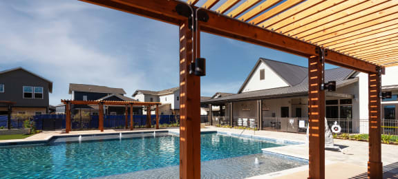 a swimming pool with a wooden structure in front of a house