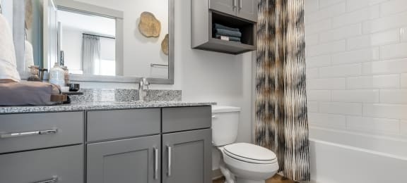 a bathroom with gray cabinets and a toilet and a shower curtain