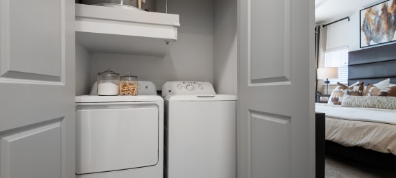 a white washer and dryer in a room next to a bedroom