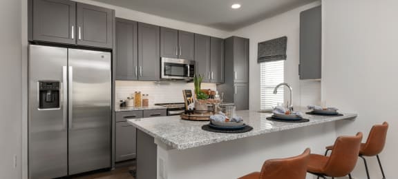 a kitchen with stainless steel appliances and a counter with chairs