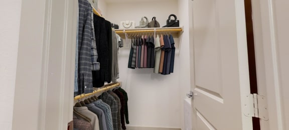 a walk in closet with clothes hanging on a rack and a door