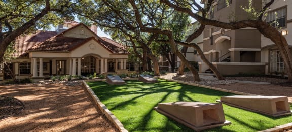 a courtyard with grass and trees in front of a building