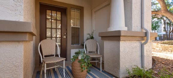 a front porch with two chairs and a potted plant