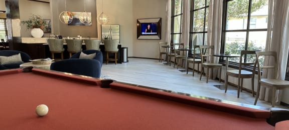 a pool table and bar in the clubhouse at the preserve at great pond apartments in windsor
