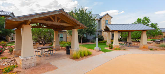 a picnic area with picnic tables and umbrellas at the whispering winds apartments in pearland