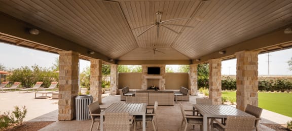 a covered patio with tables and chairs and a fireplace