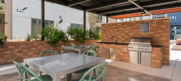 a patio with a table and chairs and an outdoor kitchen